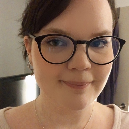 Portrait of a woman smiling at the camera with glasses and dark hair.